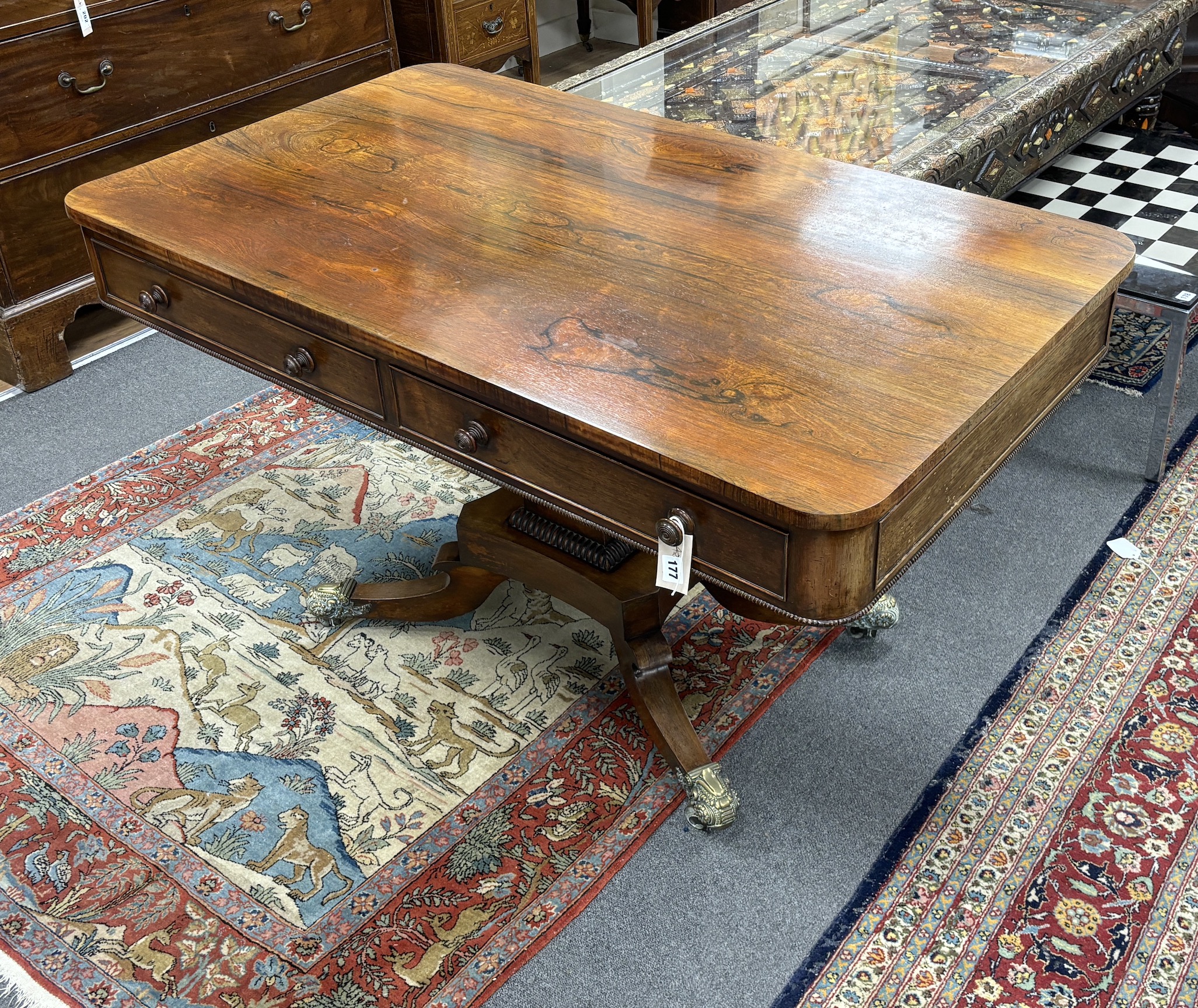A Regency rectangular rosewood centre / library table, fitted two frieze drawers and two dummy drawers on single square tapered support, quadrapartite slab base and splayed legs with brass castors, width 123cm, depth 70c